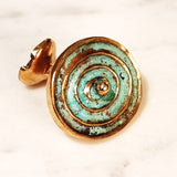 Detail of these large bronze cufflinks with patina of a blue-green colour.